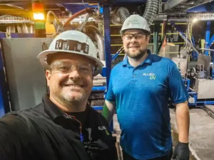 Two members of Allied UV with hard hats pose for a picture in the shop